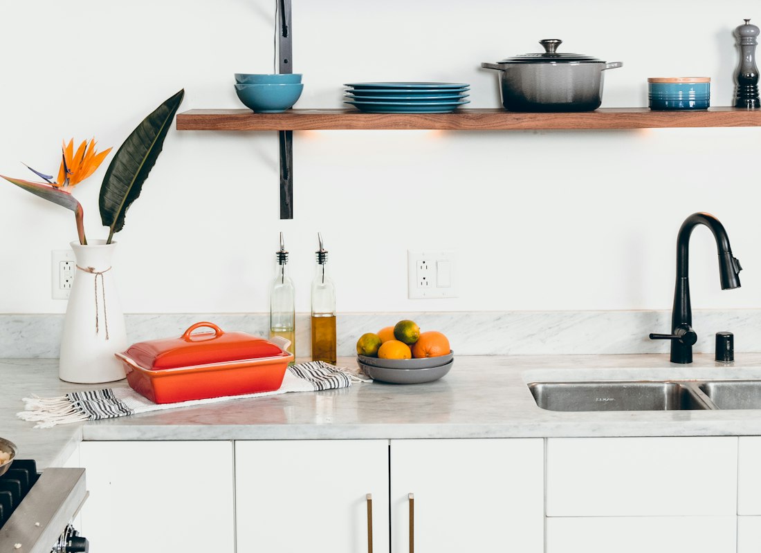 Blue glazed ceramic dinnerware stacked in a wooden drying rack