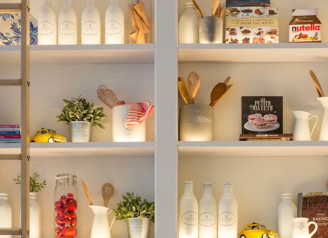 White ceramic storage jars lined up on an open kitchen shelf