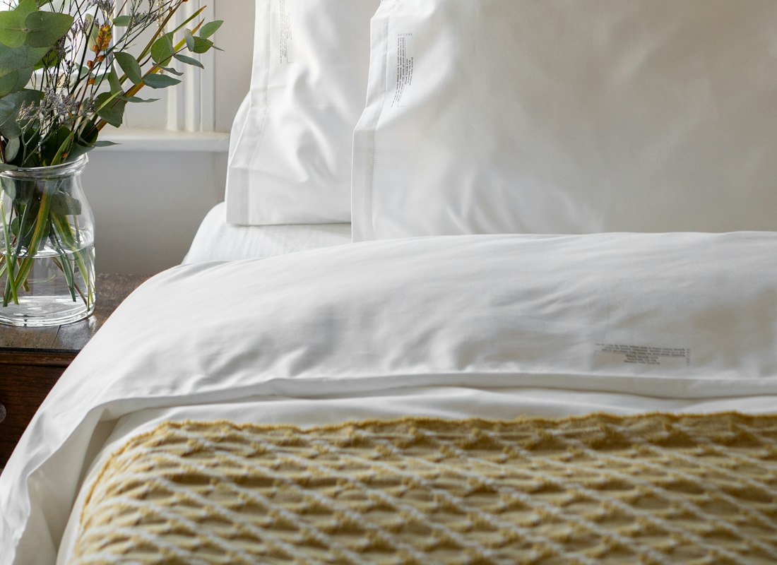 Comforter and pillows styled neatly on a bed in a bright bedroom