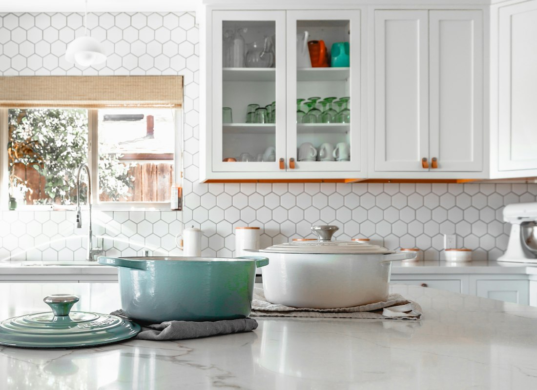 Two enamelled cooking pots resting on a kitchen island worktop