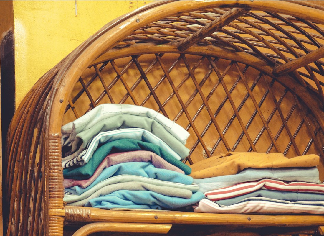 Neatly folded cotton linens stacked inside a woven basket