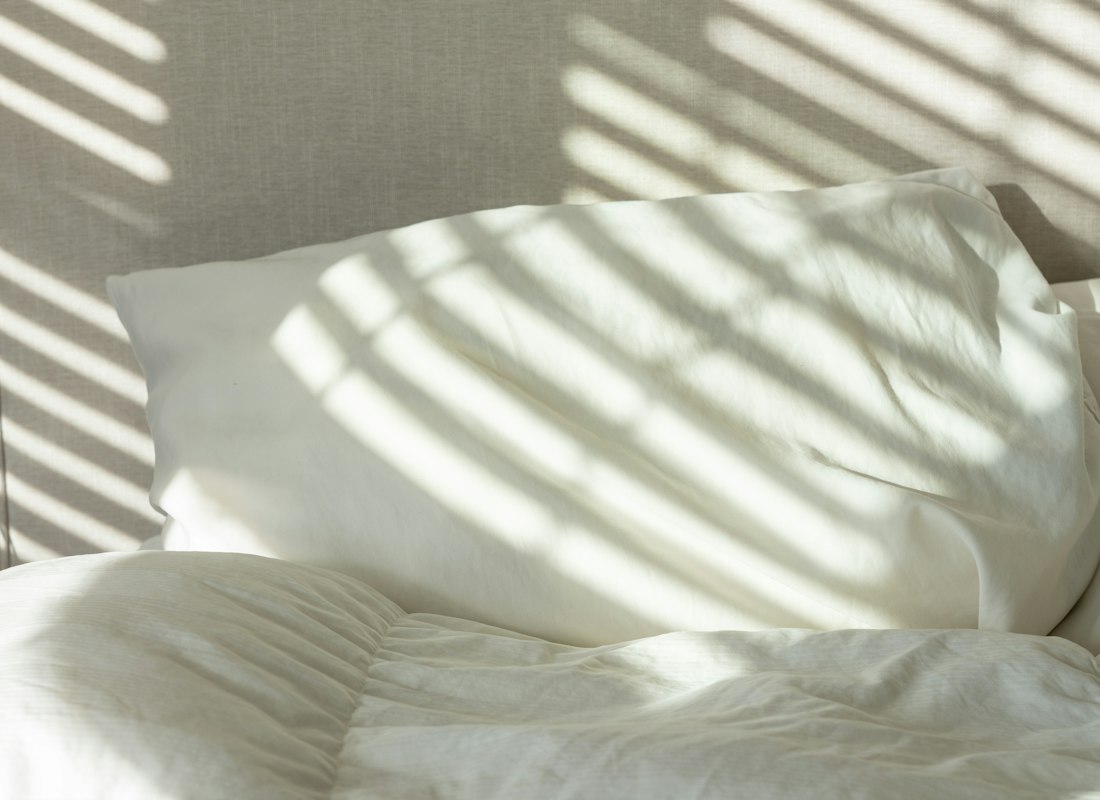 Crisp white percale bed sheets and pillows made up on a bed