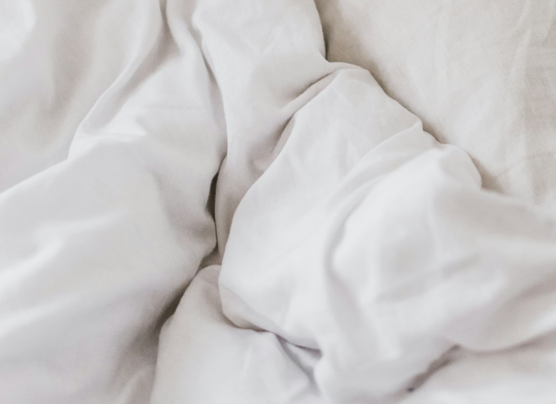 Close detail of a folded quilted white bedspread showing stitching